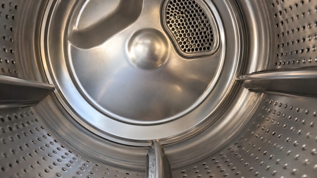 A close-up from inside a clothes dryer drum looking at its smooth empty wall